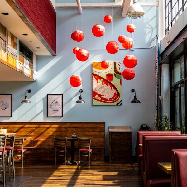 Dumpling Factory restaurant interior with light blue walls, red lanterns, and mixed seating.