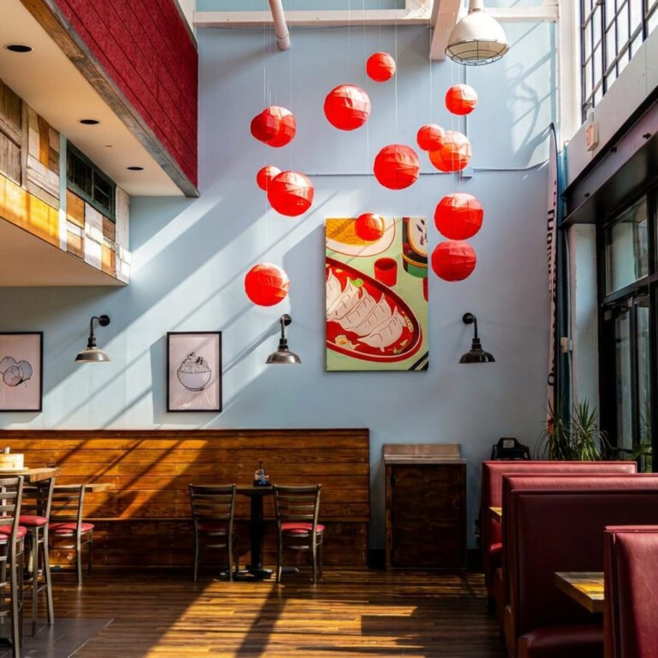 Dumpling Factory restaurant interior with light blue walls, red lanterns, and mixed seating.