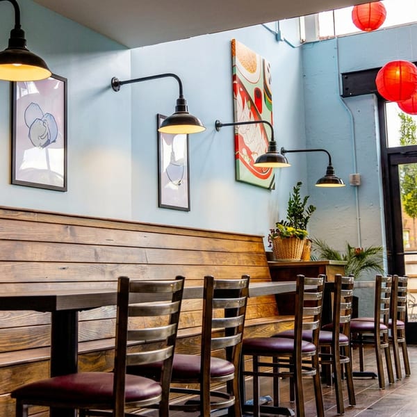 Restaurant dining area with wooden booth seating, light blue walls, industrial lights, and red paper lanterns.